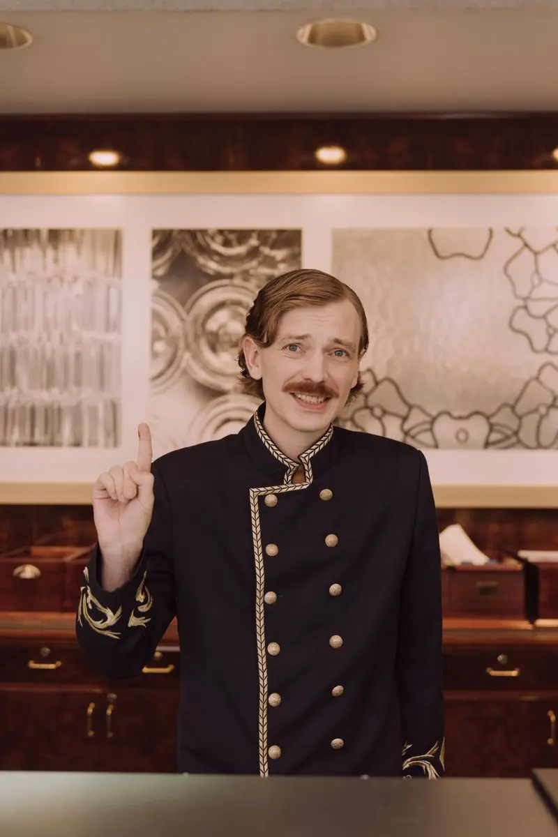 Hotel front desk agent in uniform ready to welcome guests at reception